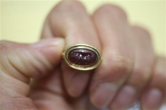 An antique yellow metal and oval carnelian cabochon ring carved with a standing bull, the shank with decorative pierced shoulders